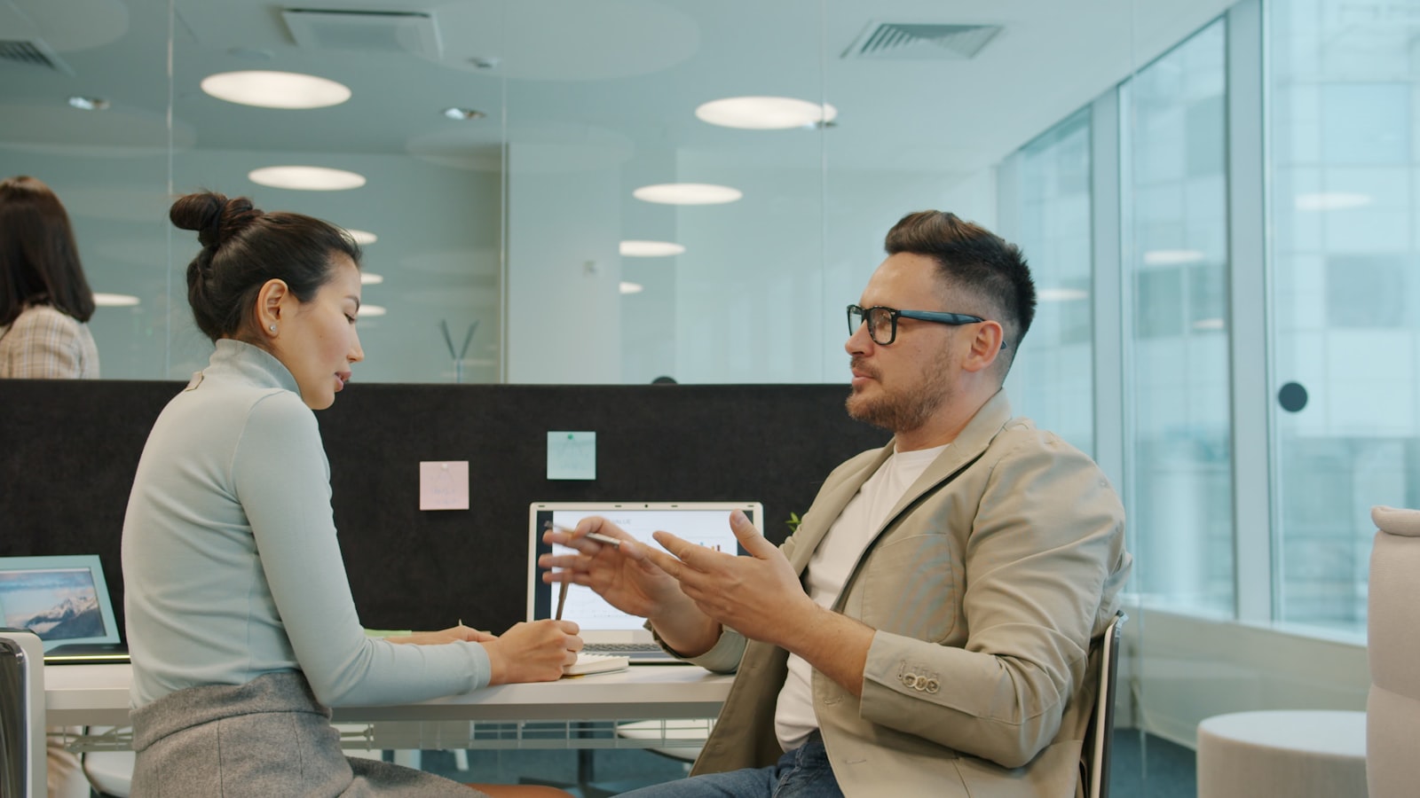Two people talking calmly across a desk in a bright office